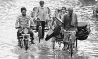 A girl carries her scooter on rickshaw on a flooded street after a downpour in Karnal on Saturday