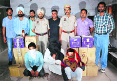 Police officials pose with the accused and the illicit liquor seized in Ludhiana on Saturday. A Tribune Photograph