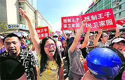 Protesters shout slogans and hold placards outside local government offices in the coastal city of Qidong, near Shanghai, on Saturday