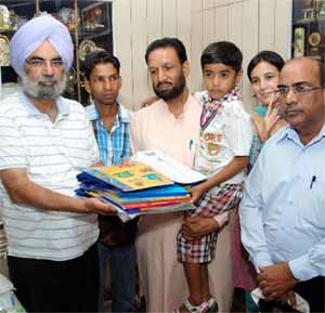 Ravinder Singh Maan (left), the principal of Dasmesh Public School, with books meant for the child Harshdeep, who has been adopted by yoga expert Radheyshyam Bansal, as his parents are undertrials in a drug related case and presently lodged in the Central Jail, Bathinda. The school will meet all the costs incurred on his studies.