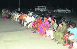 Patients and their attendants sit outside the Civil Hospital at Phase 6 in Mohali on Sunday night in the absence of a power back-up. 