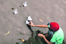 A kid floats paper boats in the water that accumulated on a road in Jalandhar on Monday morning.