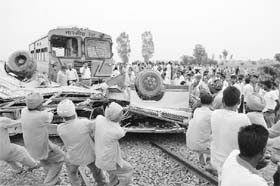 Railway employees pull the mangled remains of a school bus near Baba Bakala, Amritsar, on Monday
