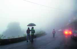 People walk in dense fog after rain in Shimla on Tuesday