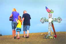 The family of a victim of the mass shooting at the Century 16 movie theatre in Aurora, Colorado, walk past a cross adorned with photographs of the victims .