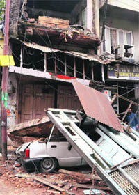 A car crushed under the debris of a building that collapsed following overnight rain in the Pakka Danga area of Jammu on Wednesday.