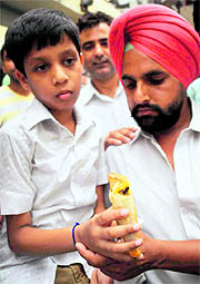 The complainant with his son holding a patty with a cockroach at the DMCH canteen in Ludhiana on Wednesday