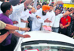 A Congress worker urges Health Minister Madan Mohan Mittal to come out of his car and receive a memorandum outside the Civil Hospital in Ludhiana on Wednesday