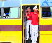 Schoolchildren stand at the door of moving buses in violation of safety norms in Amritsar.
