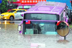 A bus sits half submerged on a flooded road in New Taipei City on Thursday. Typhoon Saola pounded Taiwan with fierce winds and torrential rain that left 