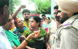 New Surajganj residents argue with SHO Surinderpal Singh demanding the cancellation of an FIR registered under the NDPS Act in Jalandhar on Friday.
