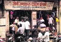 People stand outside a shop that is said to have sold a cycle used in Pune blasts.  PTI