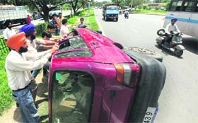 People push a car back on its wheels after it met with an acident near the Hallo Majra Chowk in Chandigarh on Saturday