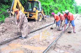 Workers clear the debris from a railway track near Mata Mansa Devi mountain at Motichur in Haridwar on Saturday