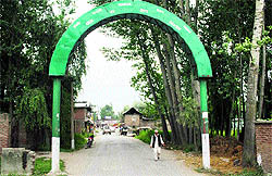 A villager walks past an arch declaring Uranhal a Model village in Anantnag district