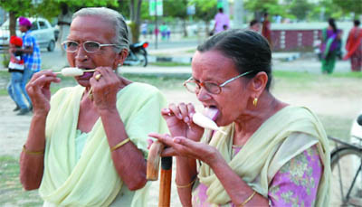Two elderly women enjoy ice-cream to beat the heat at a park in Model Town phase III on Sunday. 