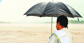 A farmer watches the Ganga which is in spate following heavy rains in Haridwar. 