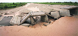A bridge built over a stream leading to the Tawi river lies damaged by flash floods on the outskirts of Jammu on Saturday
