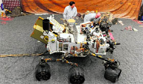 Jet Propulsion Laboratory engineers examine a full size engineered model of the Mars rover Curiosity.