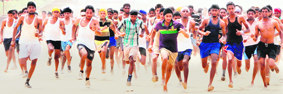 Take part in a test of physical fitness and an Army officer takes the measurements of a candidate at a recruitment drive at Khasa in Amritsar on Monday.