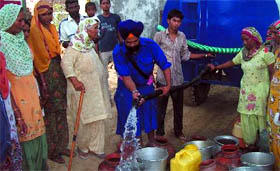 Gurmel Khalsa distributes potable water he brought in a tanker, all the way from Bathinda city, for the residents of Bir Talab village.
