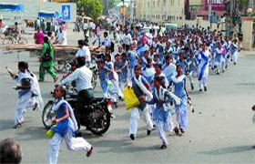 After the rehearsal, girl students cross the Hanuman Chowk  to reach their school on the Mall road amid traffic.