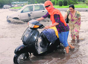 A woman and her daughter push a two-wheeler on a waterlogged road at Sector 30.