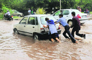 Youngsters push a car that broke down during the rain.