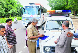 A traffic police official challans a bus driver for not following the lane system on the Janmarg at Sector 9 in Chandigarh on Monday. 