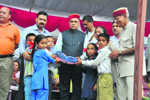 Chief Minister PK Dhumal distributes the school uniform among students in Chamba on Monday.