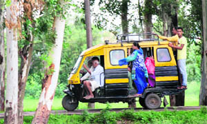 Passengers clamber on to a moving autorickshaw at Suchetgarh village in Jammu on Monday.