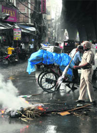 A policeman clears a road of a burning effigy at the Clock Tower in Ludhiana on Monday
