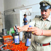 A police official shows seized bottles of adulterated cold drinks and beer at a factory in Chandigarh on Tuesday.