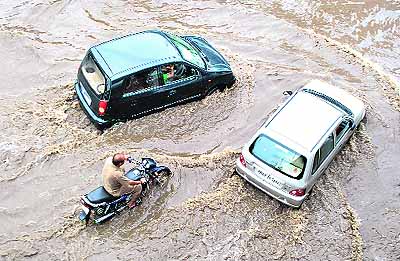 Motorists wade through a waterlogged road after heavy showers in Patiala on Tuesday. 