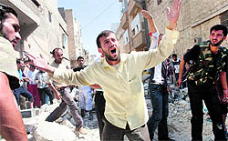 A Syrian man shouts as residents gather at the scene of a bombed building purportedly hit during Syrian army shelling in Aleppo