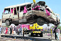 A damaged bus which was hit by a remote control bomb is lifted by a crane in Kabul