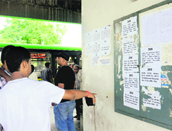 Commuters find it hard to read the CTUs bus routes pasted on a wall at the Sector 43 ISBT.
