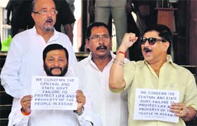 MPs from Asom Gana Parishad raise slogans against ethnic violence in their state, outside Parliament House in New Delhi on Wednesday