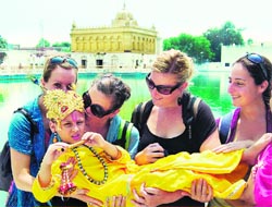 Foreigners carry a child dressed as Lord Krishna on the eve of Janamashtami at the Golden Temple in Amritsar on Thursday. photo: sameer sehgal