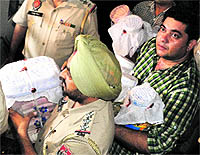 Police personnel carry jewellery and currency notes recovered from Fizas house at Sector 48 in Mohali on Thursday
