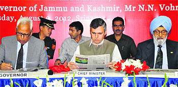 Chief Minister Omar Abdullah reads a copy of Kashmir Tribune after its launch in Srinagar on Thursday. He is flanked by Governor NN Vohra and President of The Tribune Trust Justice SS Sodhi (retd)