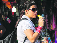 A tourist relishes an ice candy during a hot sunny day in Jammu on Thursday