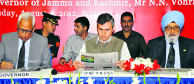 Chief Minister Omar Abdullah reads a copy of Kashmir Tribune after its launch in Srinagar on Thursday. He is flanked by Governor NN Vohra and President of The Tribune Trust Justice (retd) SS Sodhi.