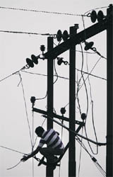 A Power Development Department employee repairs a wire in Jammu.