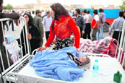 An Iranian woman stands next to her injured child outside a hospital in the town of Ahar, some 60 km east of Tabriz, on Saturday.  AFP