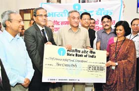 A cheque for Rs 2 crore being presented by officials of the SBI to Chief Minister Vijay Bahuguna for Uttarkashi victims in Dehradun on Sunday