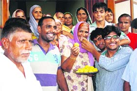 Yogeshwar Dutts mother, Shushila Devi, offers laddoos to visitors at Bhainswal Kalan village in Sonepat district