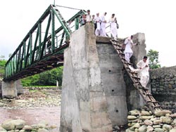 Women climb down the bridge on Candya nullah at Palma village, Rajouri. A Tribune photograph