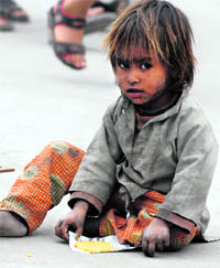 A destitute child has her meals on a footpath in Srinagar on Sunday.