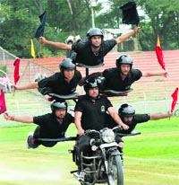 Jammu and Kashmir Police personnel perform a stunt on a motorcycle during a rehearsal for the Independence Day parade at the Bakshi stadium in Srinagar on Monday. Photo: Amin War